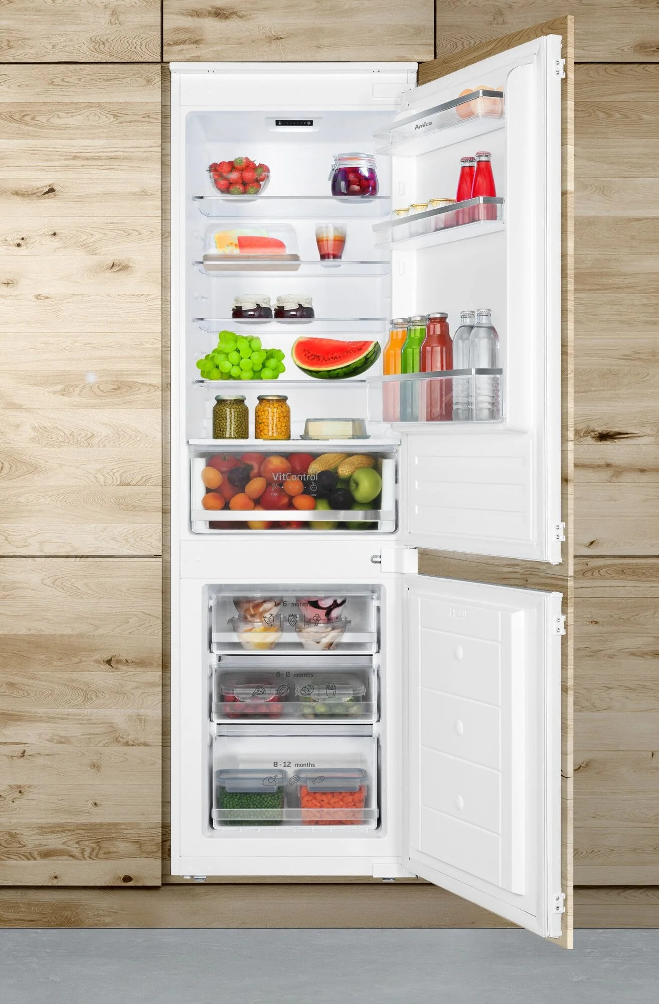 Otwarta lodówka wypełniona owocami, warzywami i napojami. Drewniane panele po bokach. Widoczna zamrażarka.