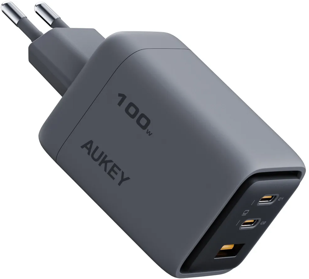 Un caricabatterie AUKEY grigio da 100W con due porte USB-C e una porta USB-A. Ha due spine argentate.