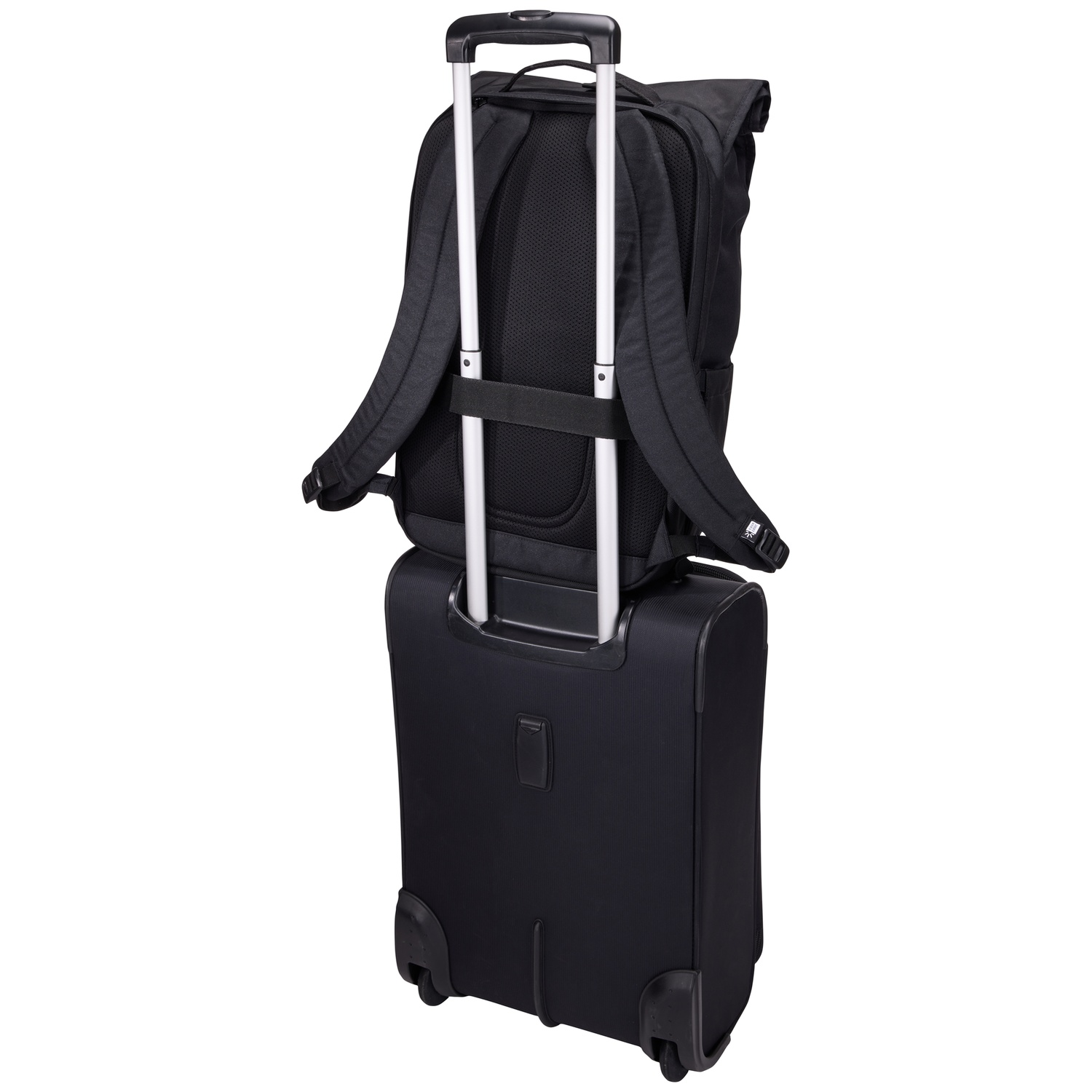 Un sac à dos noir repose sur une valise à roulettes noire. Les deux sont contre un fond blanc. La poignée de la valise est étendue.