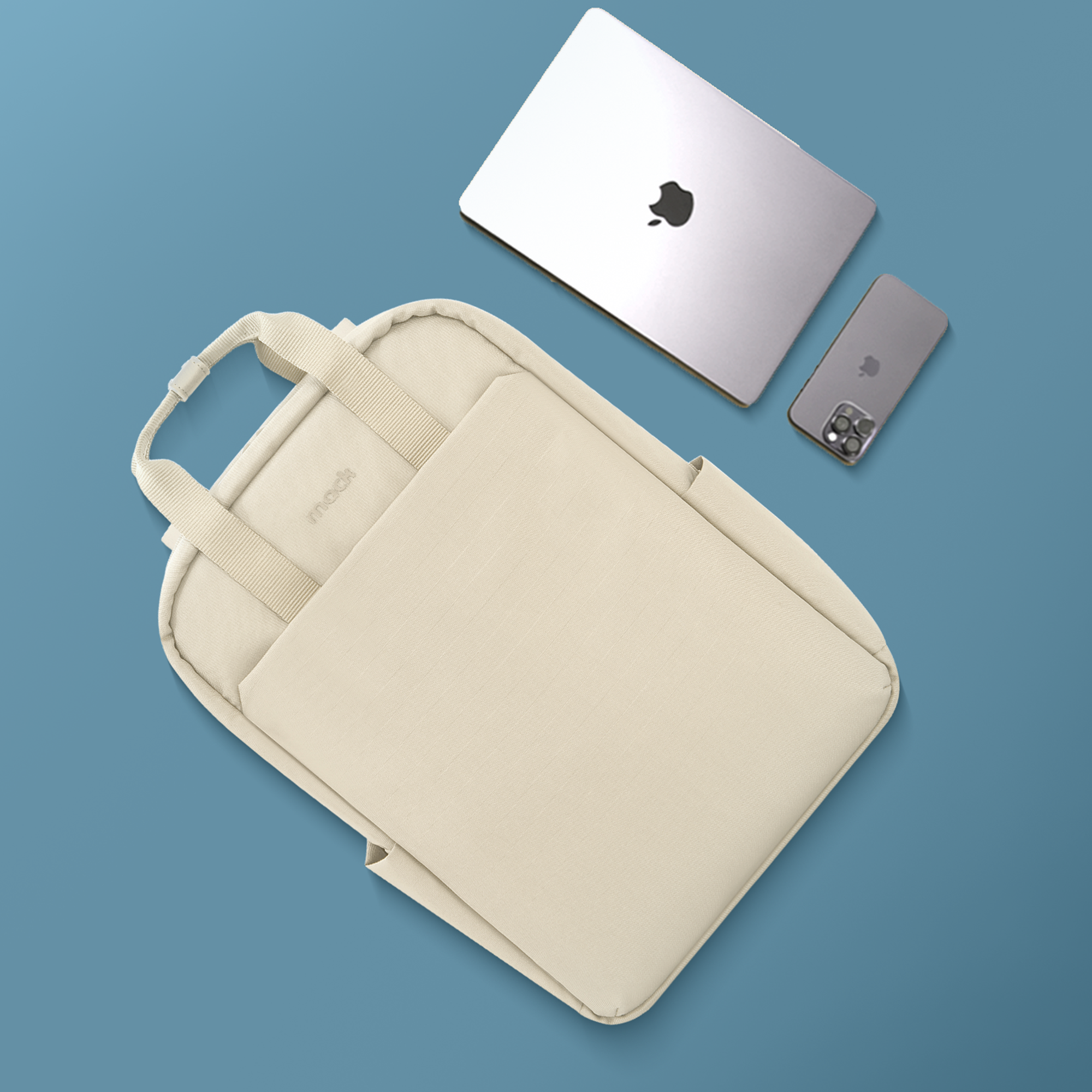 Krem rengi çanta, dizüstü bilgisayar ve telefon mavi arka plan üzerinde. Dizüstü ve telefonda Apple logosu var.