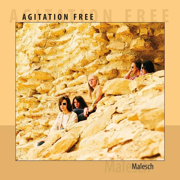 Bandmitglieder auf einer Felsformation. Die Band heißt Agitation Free. Der Hintergrund ist eine goldene Felsformation.