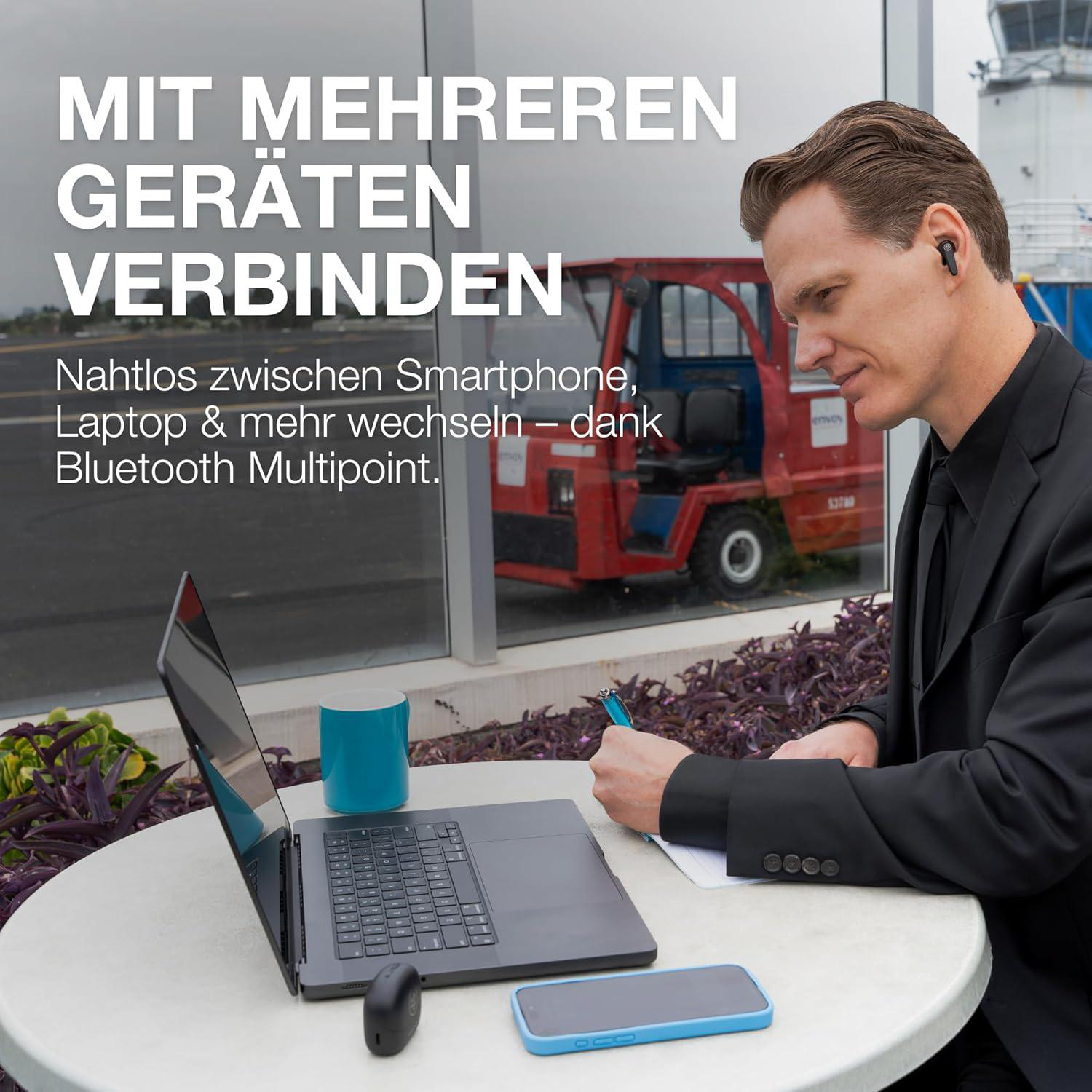 Ein Mann im Anzug benutzt einen Laptop. Ein Telefon und eine Tasse stehen auf dem Tisch. Text auf dem Bild lautet 'Verbinden Sie sich mit mehreren Geräten'.