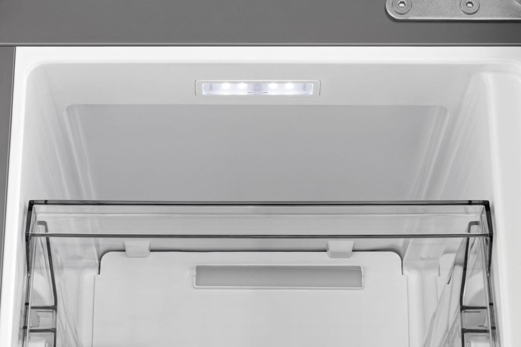 Innerhalb eines weißen Kühlschranks. Eine transparente, ausziehbare Schublade befindet sich im unteren Teil. Ein kleiner Lichtstreifen befindet sich über der Schublade.