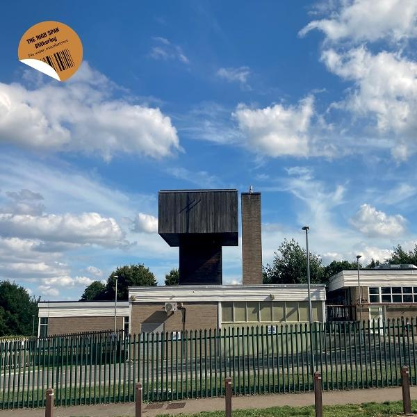Ein Gebäude mit einer einzigartigen, erhöhten Holzkonstruktion. Ein bewölkter blauer Himmel ist die Kulisse. Ein Aufkleber befindet sich oben links.