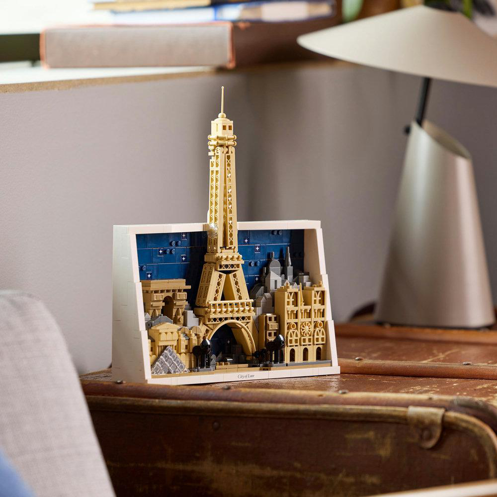 Ein Lego-Modell von Paris mit Eiffelturm, Arc de Triomphe und anderen Gebäuden. Auf einer Holzoberfläche ausgestellt.