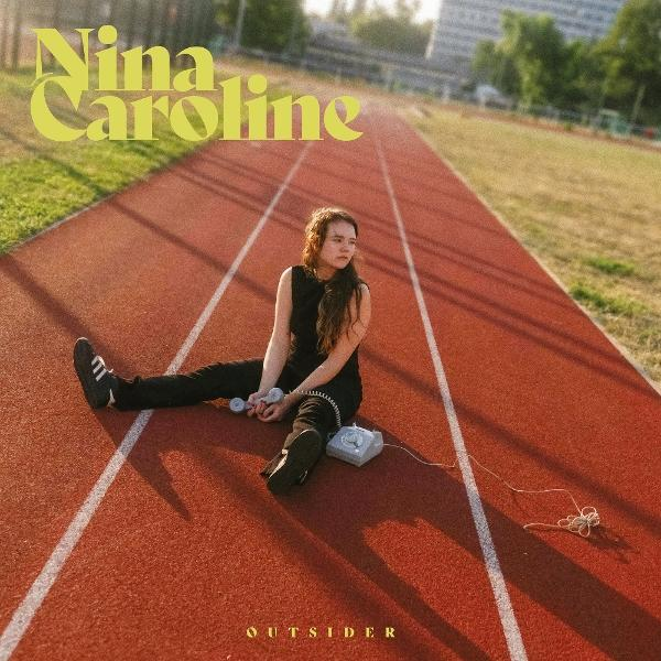 Eine Frau sitzt mit einem Telefon auf einer roten Bahn. Der Text 'Nina Caroline' steht darüber. Das Wort 'OUTSIDER' steht unten.
