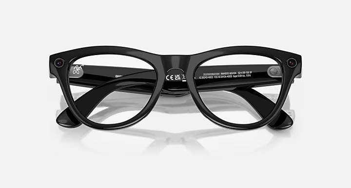 Czarne inteligentne okulary z przezroczystymi soczewkami, dwiema małymi kamerami i białym tłem. Okulary mają nowoczesny design.