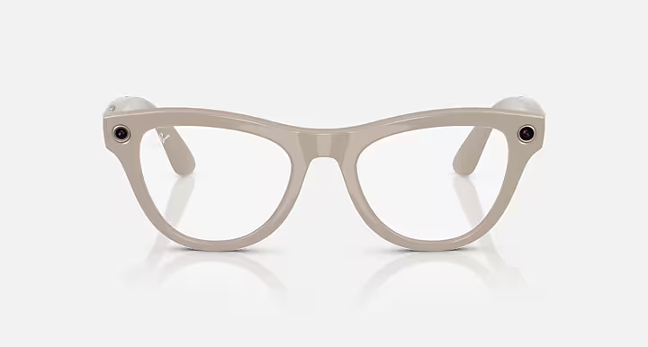 Jasnoszare okulary z przezroczystymi soczewkami. Oprawki mają kształt kociego oka, z małymi kamerami na zausznikach i logo Ray-Ban.