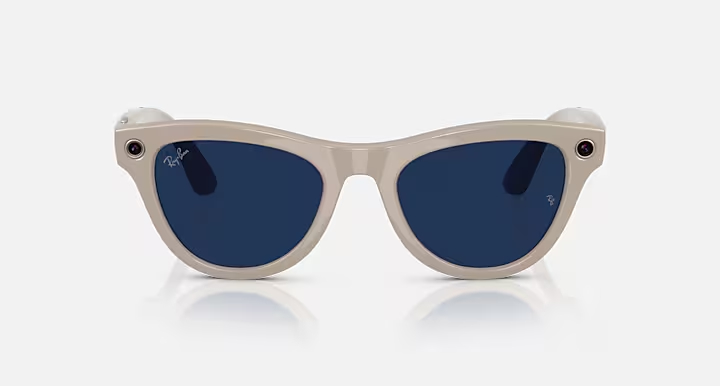 Para beżowych inteligentnych okularów Ray-Ban z ciemnoniebieskimi soczewkami, aparatem po bokach i logo Ray-Ban.