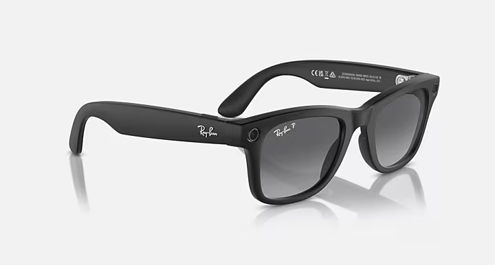Czarne okulary przeciwsłoneczne Ray-Ban z szarymi soczewkami gradientowymi. Logo 'Ray-Ban' na zausznikach. Poniżej odbijająca powierzchnia.