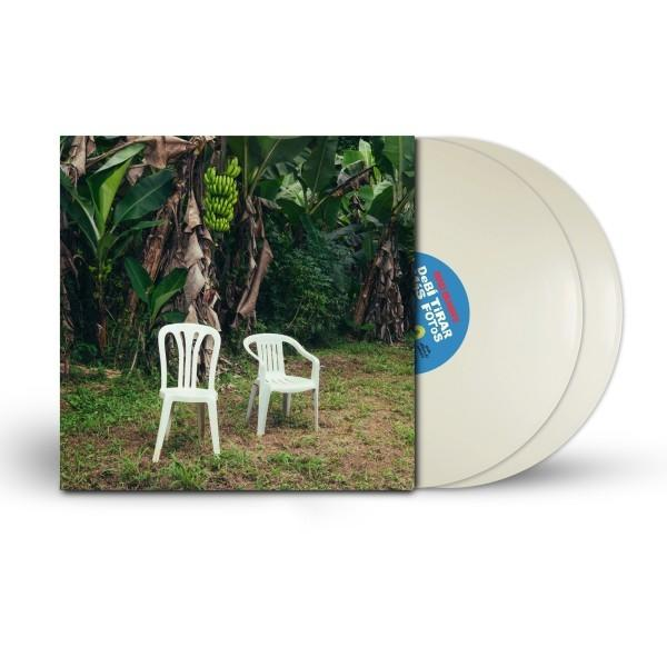 Zwei weiße Plastikstühle auf Gras in der Nähe von Bananenbäumen. Rechts eine Schallplatte. Das Albumcover ist sichtbar.