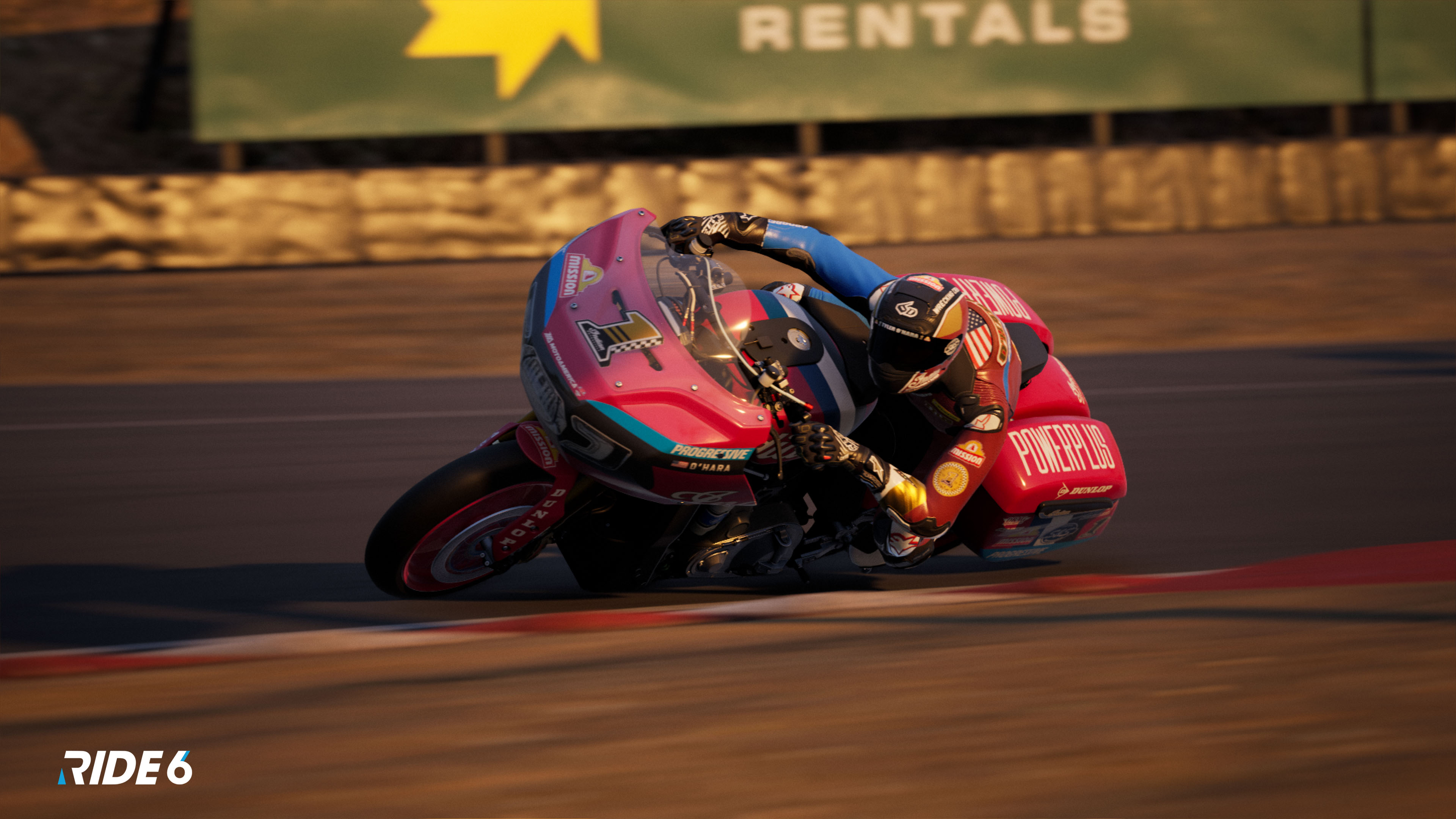 Ein Motorrad fährt auf einer Rennstrecke und neigt sich in eine Kurve. Der Fahrer trägt einen rot-schwarzen Anzug mit Helm.