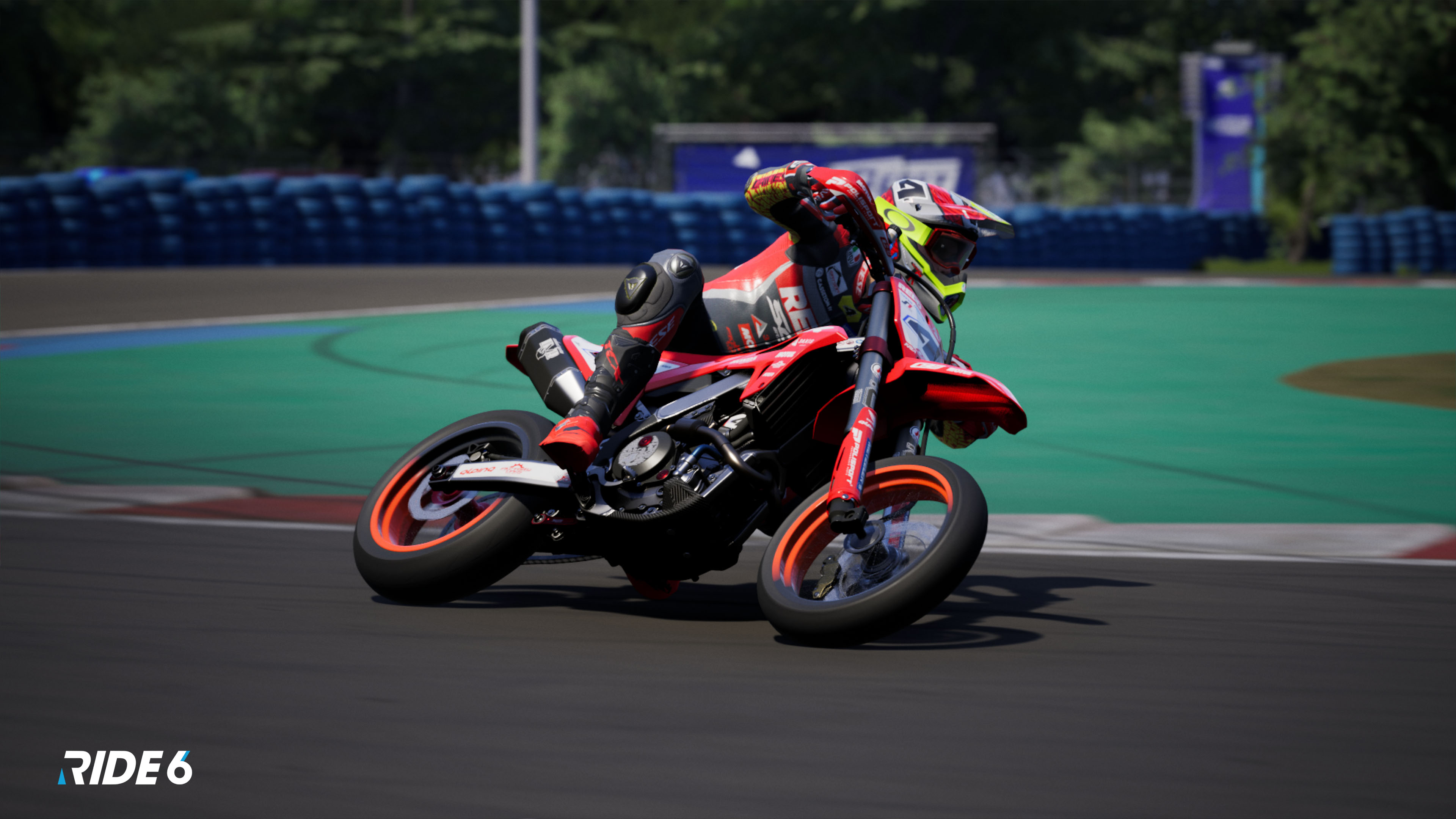 Ein Motorradfahrer lehnt sich in einer Kurve auf einem rot-schwarzen Motorrad auf einer Rennstrecke. Die Strecke ist grün und schwarz.