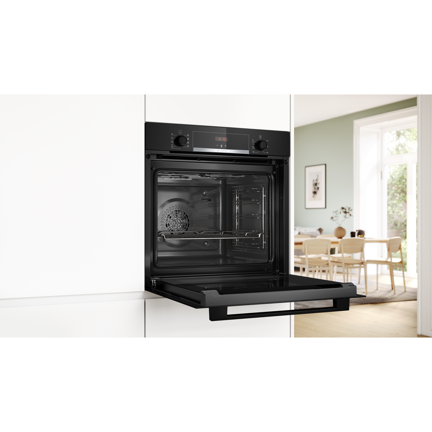 Zwarte oven, deur open, met interne roosters. Witte kasten links, eetkamer zichtbaar op de achtergrond.