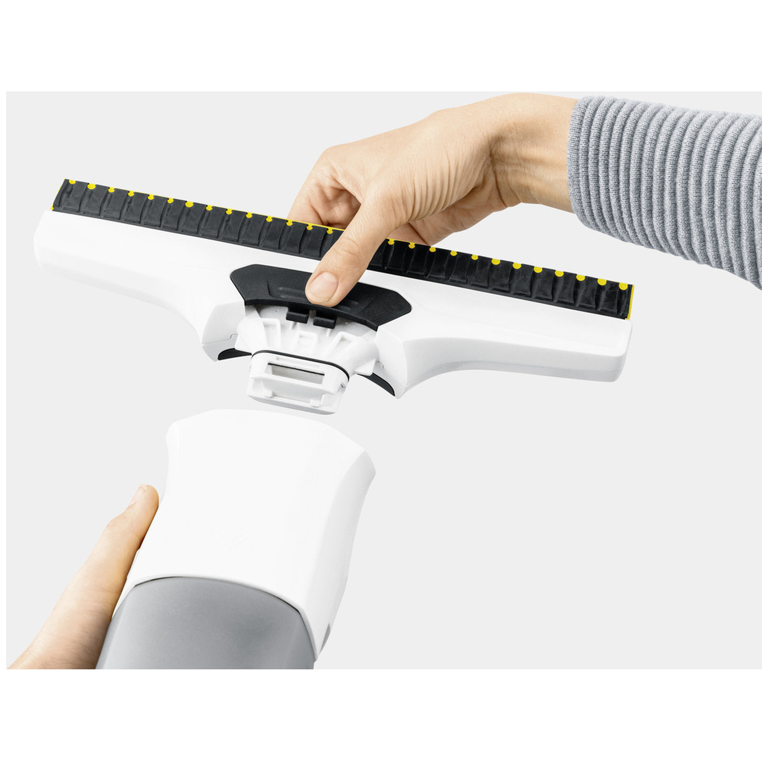 A person assembling a white and black cleaning tool. The tool is in two parts. The person's hands are visible.