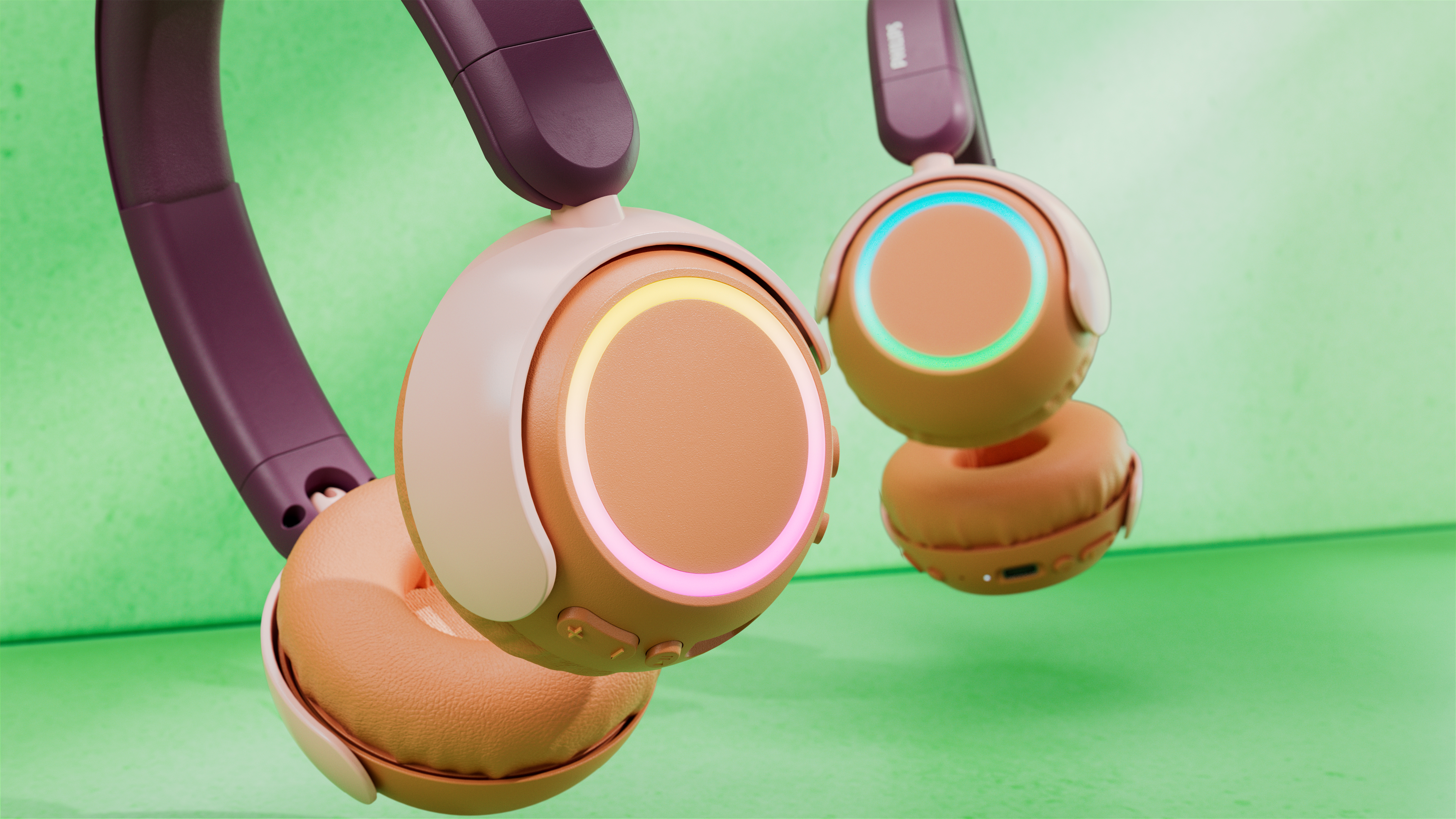 Zwei kabellose Kopfhörer mit beleuchteten Ohrmuscheln. Farben sind Beige, Rosa und Lila. Der Hintergrund ist ein strukturiertes Grün.