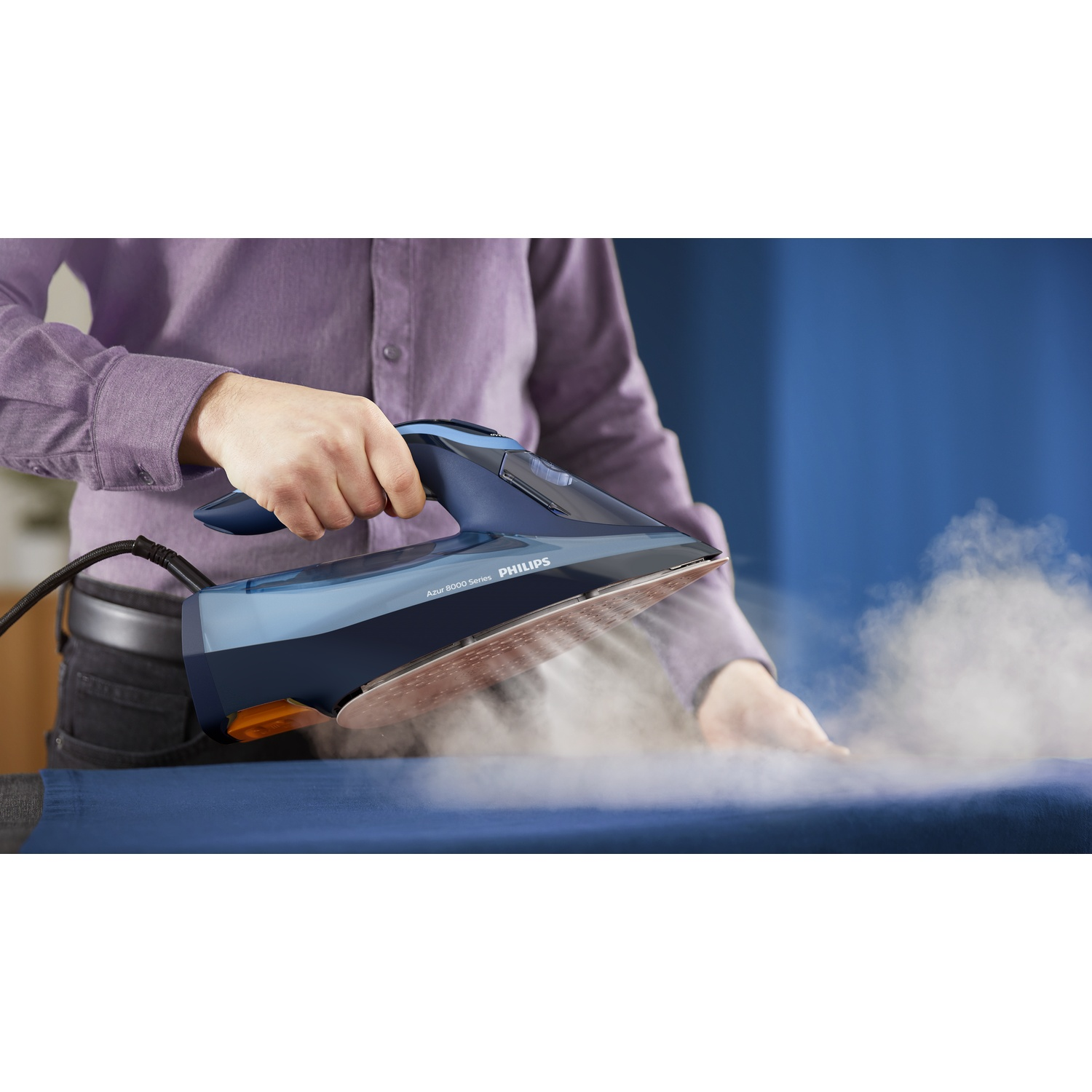 Une personne repassant un tissu bleu avec un fer à repasser Philips bleu et noir, vapeur visible. Fond : mur bleu, personne portant une chemise violette.