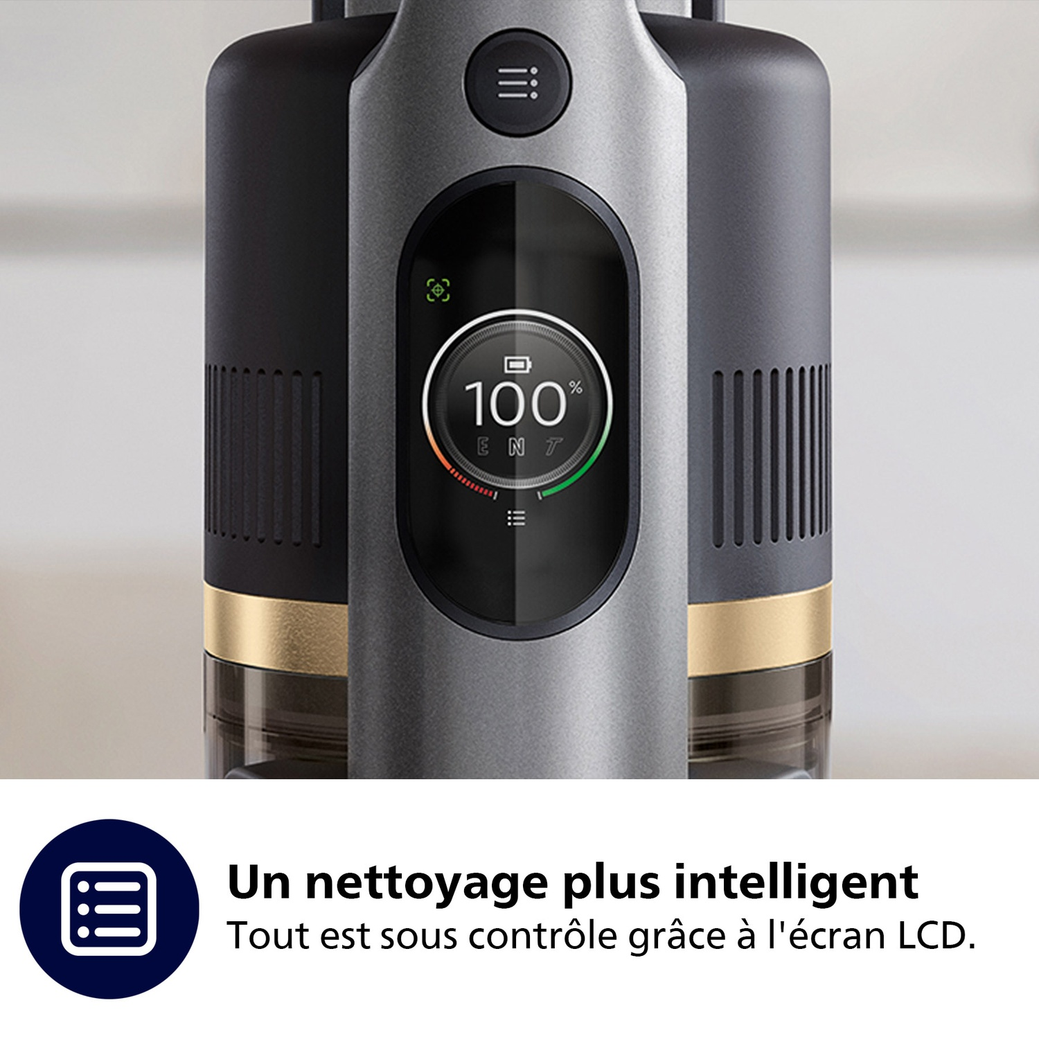 Gros plan d'un aspirateur avec un affichage numérique indiquant une charge de 100 %. L'aspirateur est noir, gris et doré.