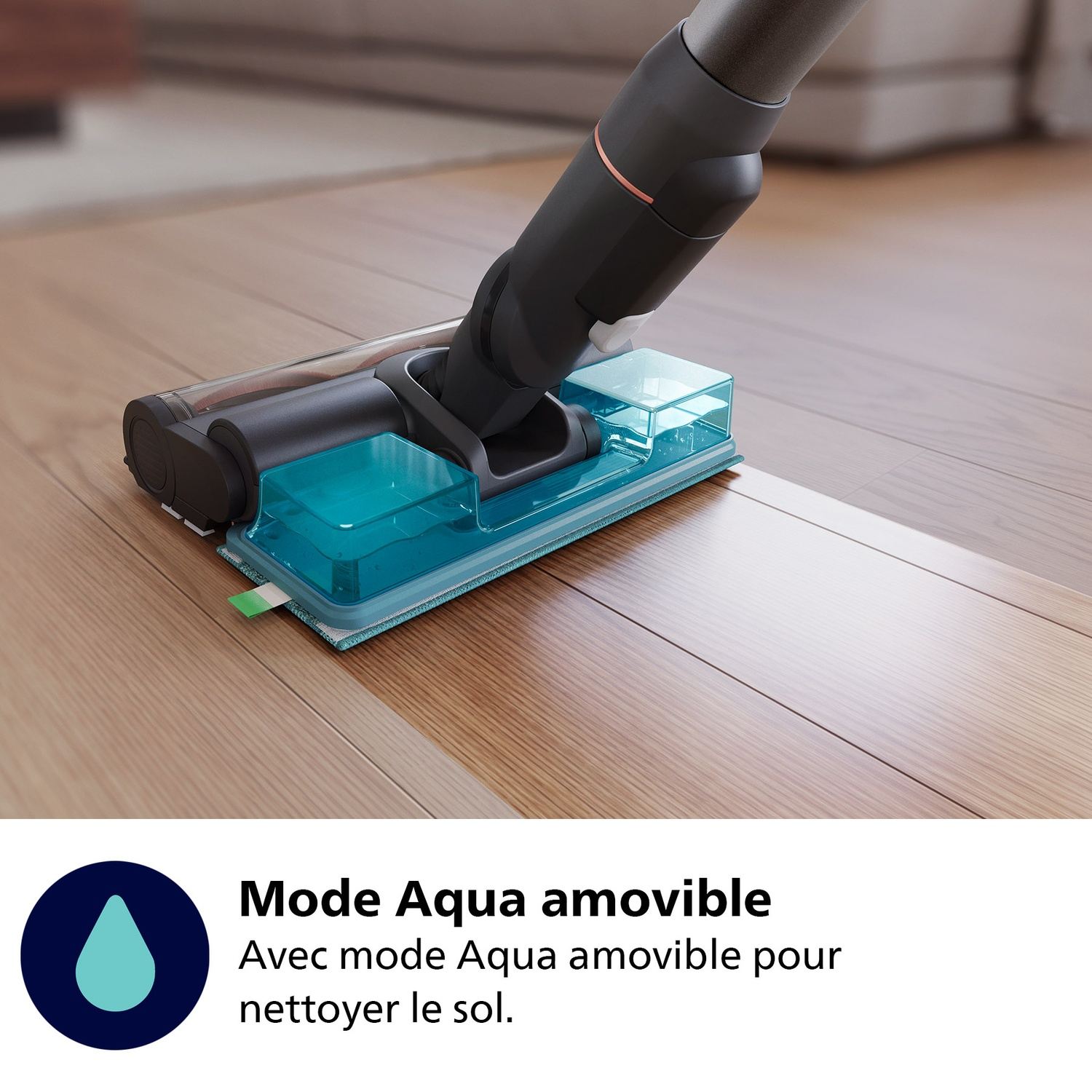 Gros plan d'une tête d'aspirateur avec un réservoir d'eau, posée sur un plancher en bois. Le nettoyeur est noir et gris.