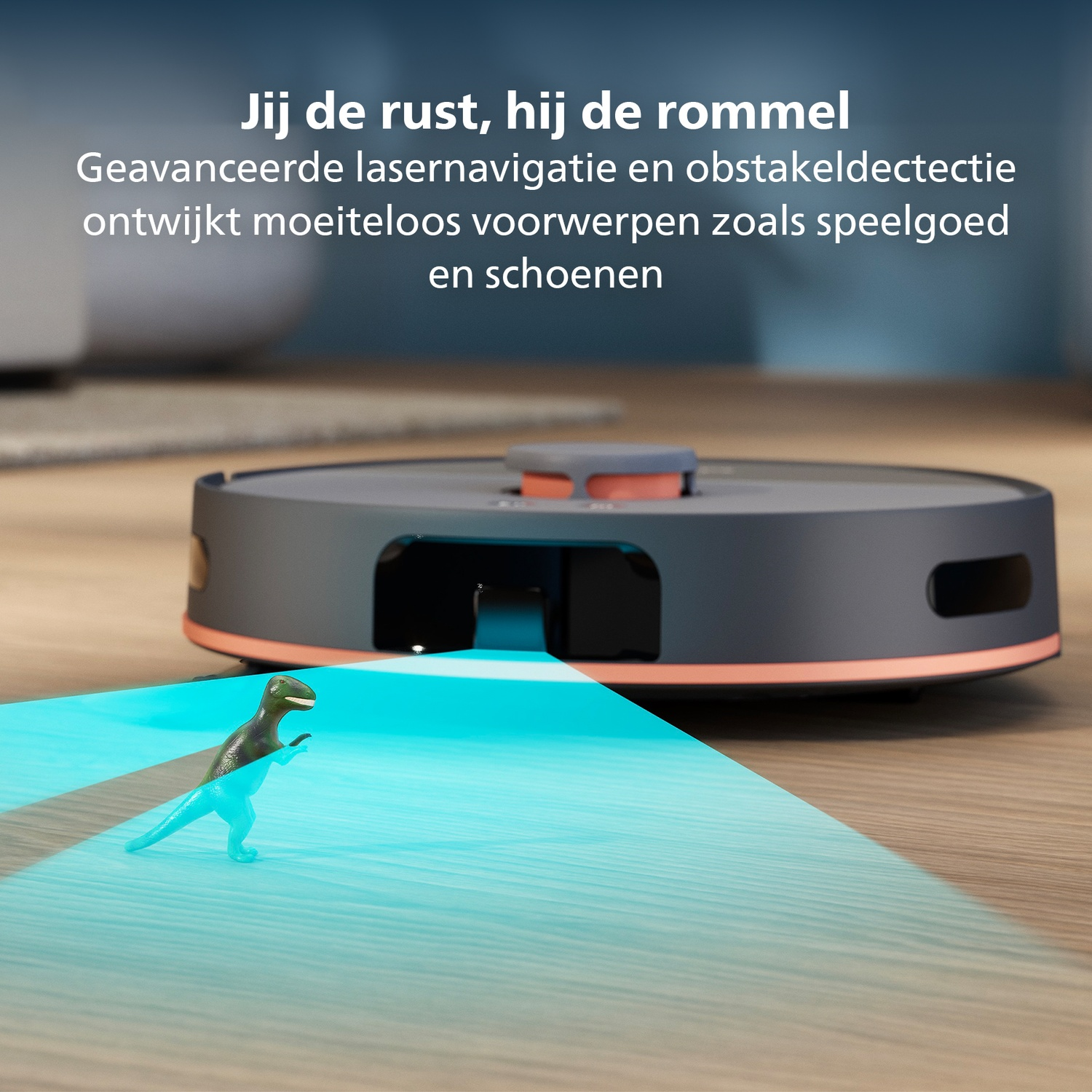 A robot vacuum cleaner with a dinosaur toy in front. The vacuum cleaner is black and orange, on a wooden floor.