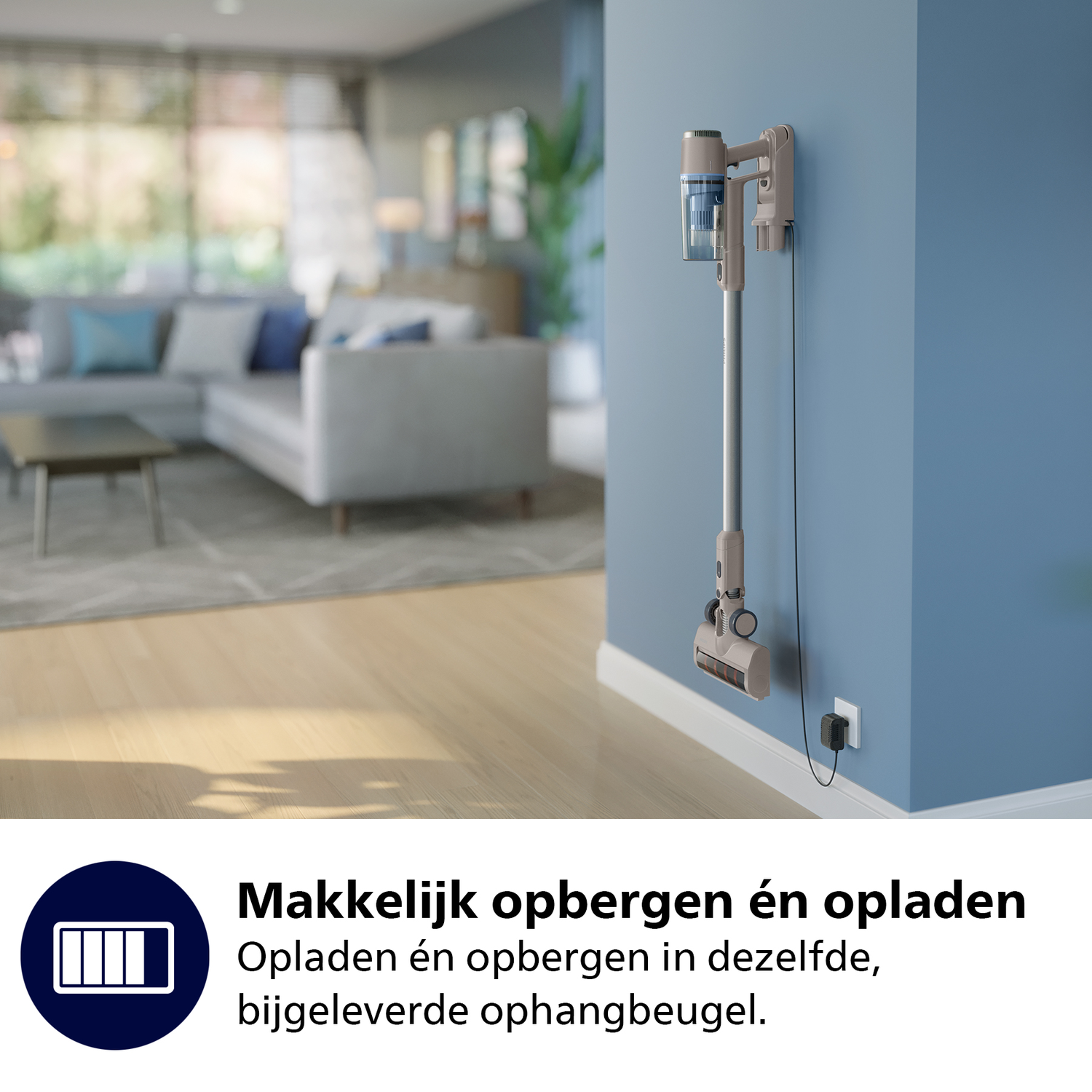 A cordless vacuum cleaner hanging on a blue wall. The vacuum is gray and blue. A power outlet is below.