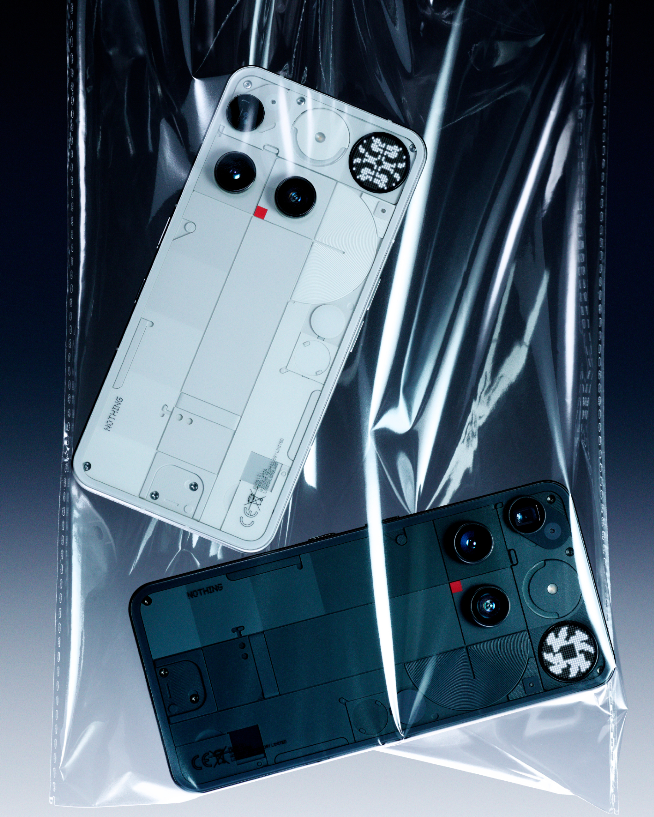 Zwei Nothing Phone (1) Handys in einer Plastiktüte. Eines weiß, eines schwarz. Beide zeigen interne Komponenten.