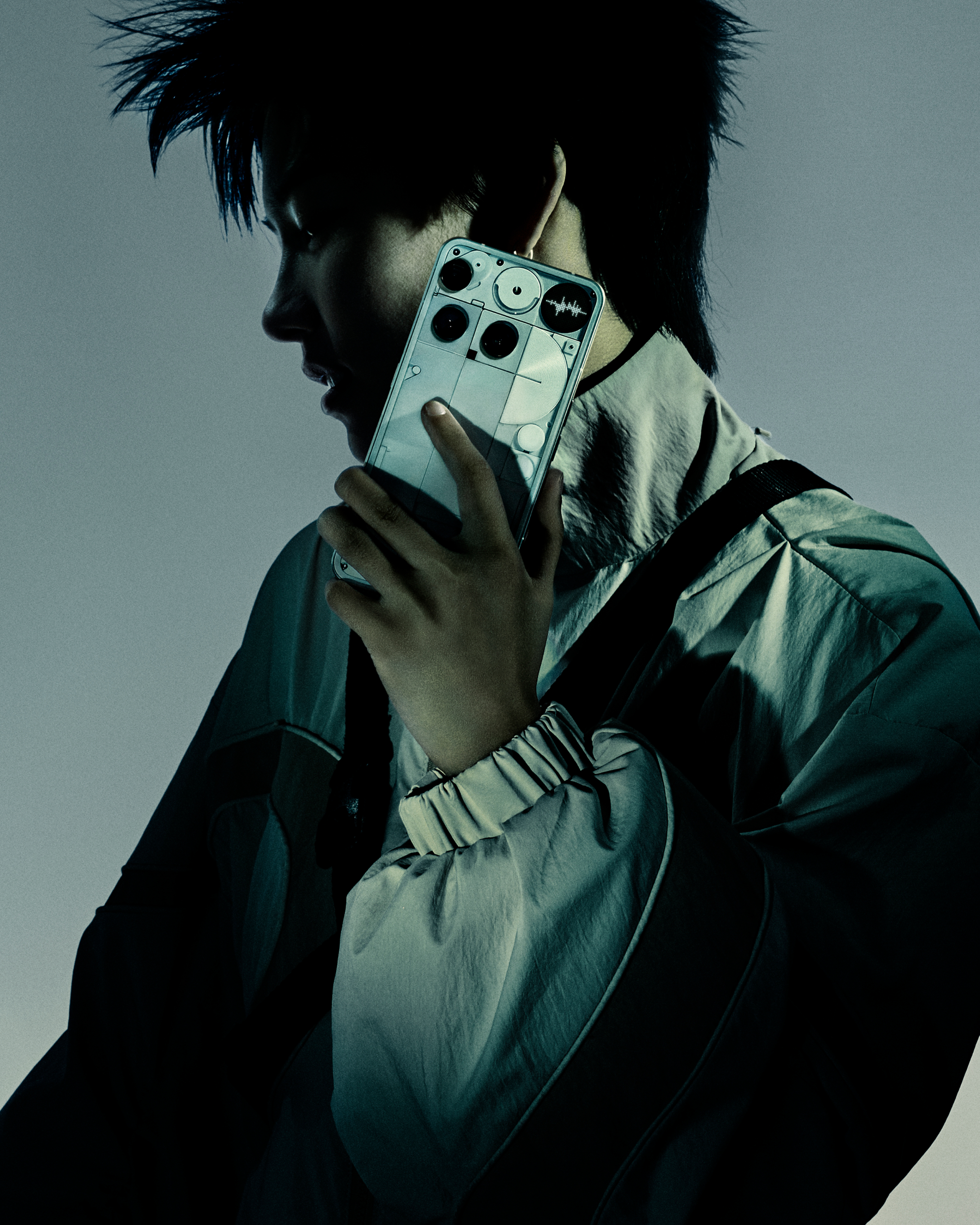 Person hält ein Smartphone. Das Telefon hat ein einzigartiges Design. Die Person trägt eine Jacke.