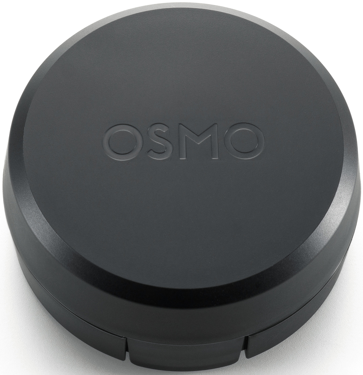 Eine schwarze Osmo-Kameraobjektivkappe. Das Wort OSMO ist oben eingeprägt. Die Kappe ist kreisförmig und liegt auf weißem Grund.