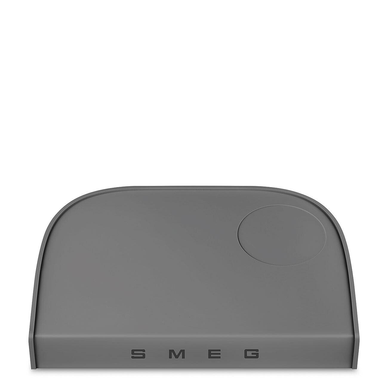 Eine graue Smeg-Gerätematte. Sie hat eine gebogene Oberseite und die Buchstaben S, M, E, G sind unten sichtbar. Eine kreisförmige Vertiefung befindet sich oben rechts.