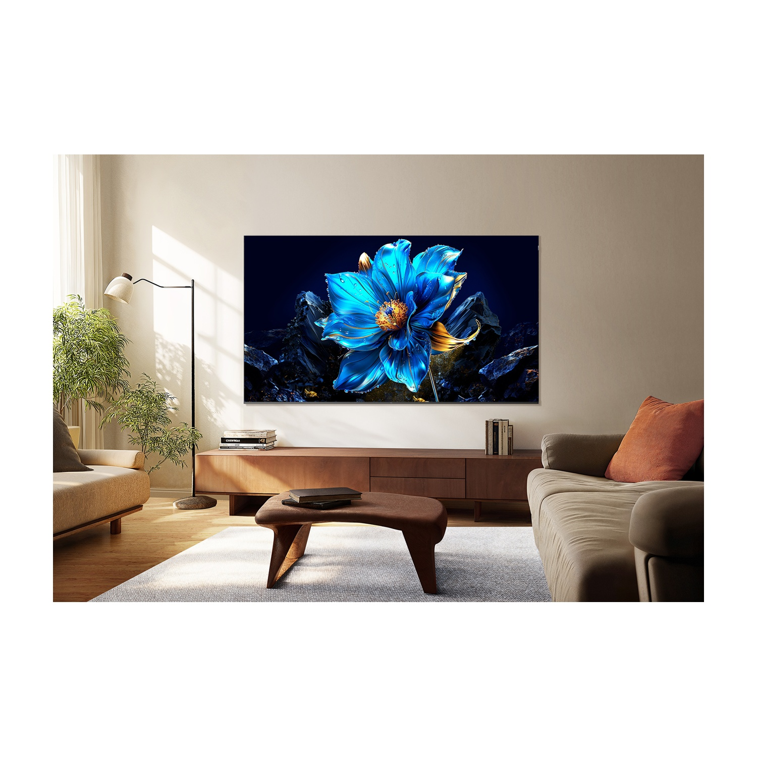 Soggiorno con grande TV con fiore blu. C'è un divano, un tavolino e un tappeto. La luce del sole entra da una finestra.
