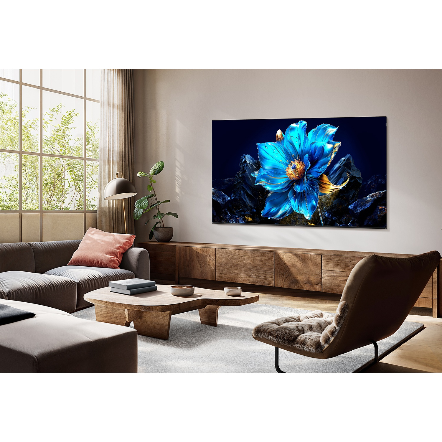Soggiorno con una grande TV che mostra l'immagine di un fiore blu. Sono presenti anche un divano grigio, mobili in legno e una sedia.