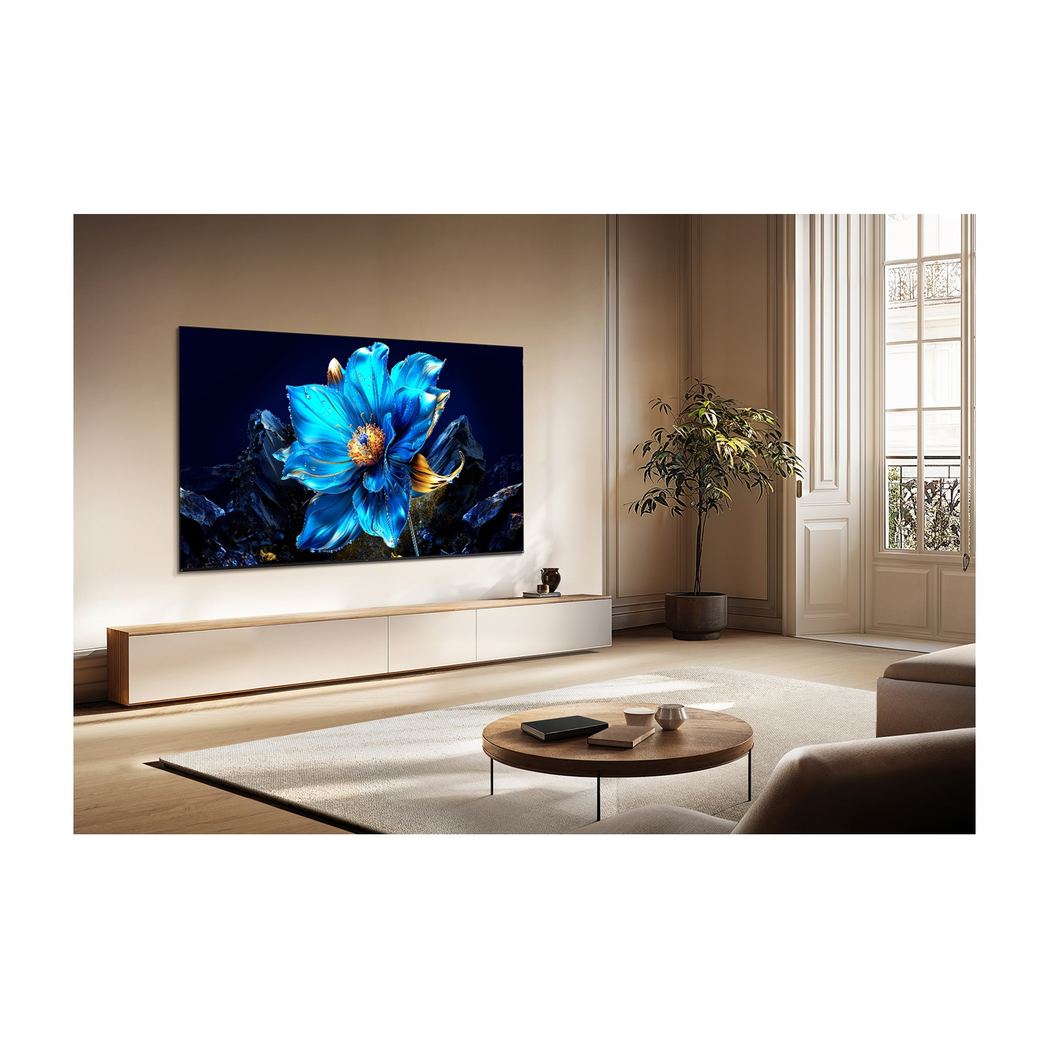 Soggiorno con grande TV che mostra un fiore blu. Sotto un mobile bianco, un tavolo rotondo, una pianta e una finestra sono visibili.