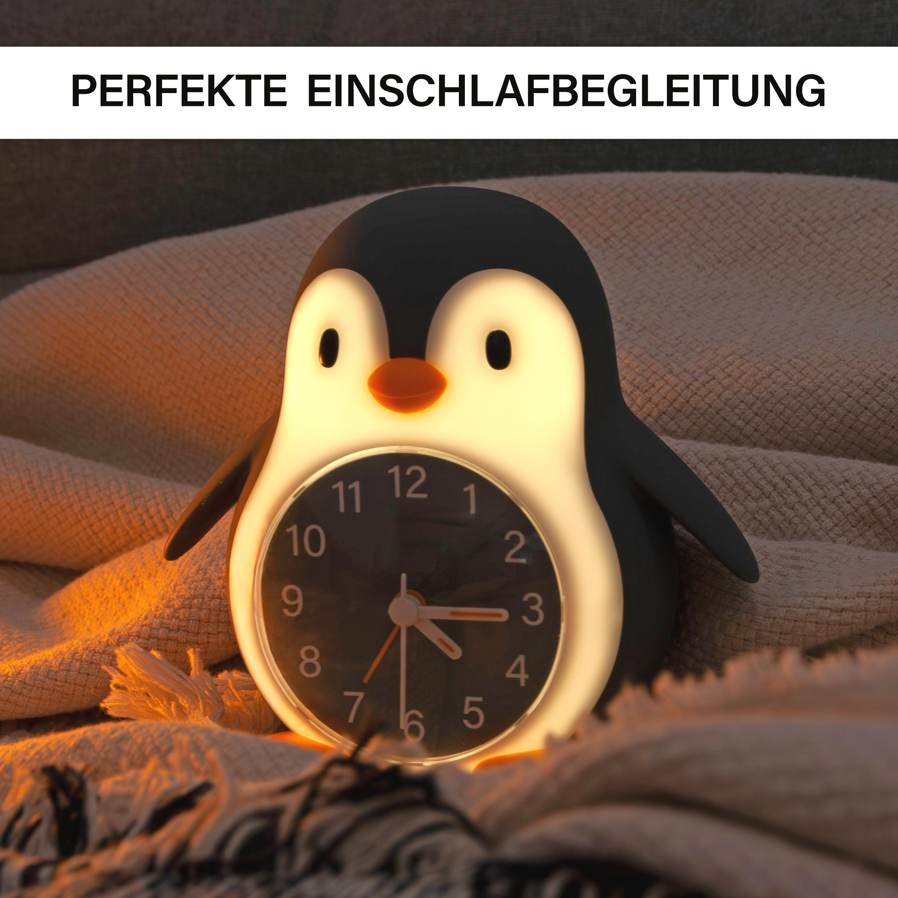 Eine pinguinförmige Uhr auf einer strukturierten Decke. Das Zifferblatt zeigt die Uhrzeit an. Die Szene ist warm beleuchtet.