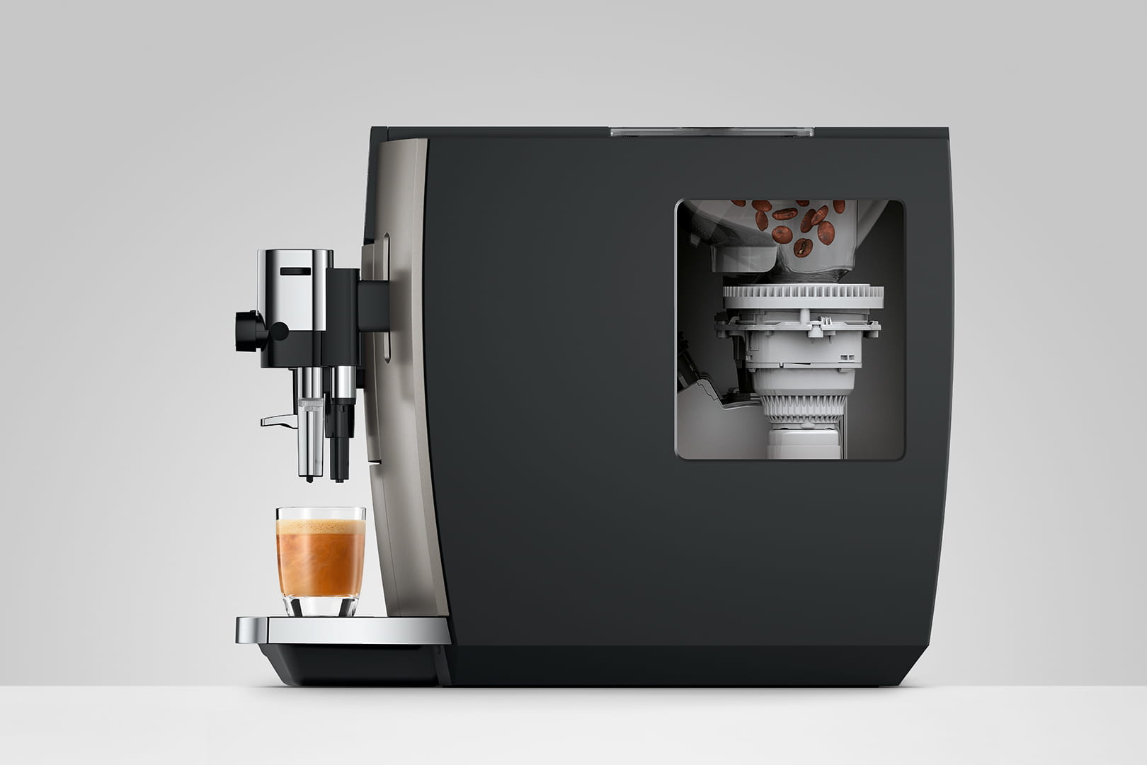 Macchina da caffè con un bicchiere di caffè. La macchina ha una sezione trasparente che mostra chicchi di caffè e parti del macinacaffè.
