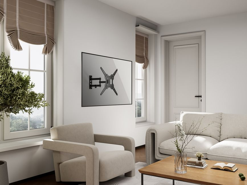 Salon avec une télévision fixée au mur. Meubles beiges et une table en bois. Fenêtres avec stores et une porte.
