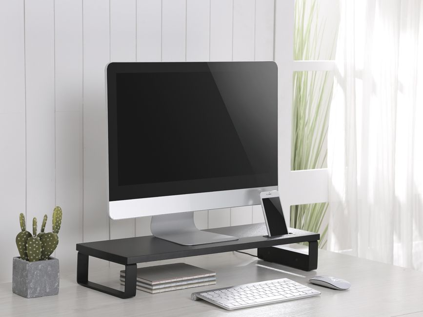 Un écran d'ordinateur, un téléphone, un clavier et une souris sur un bureau. Un cactus est à gauche. Une fenêtre est en arrière-plan.