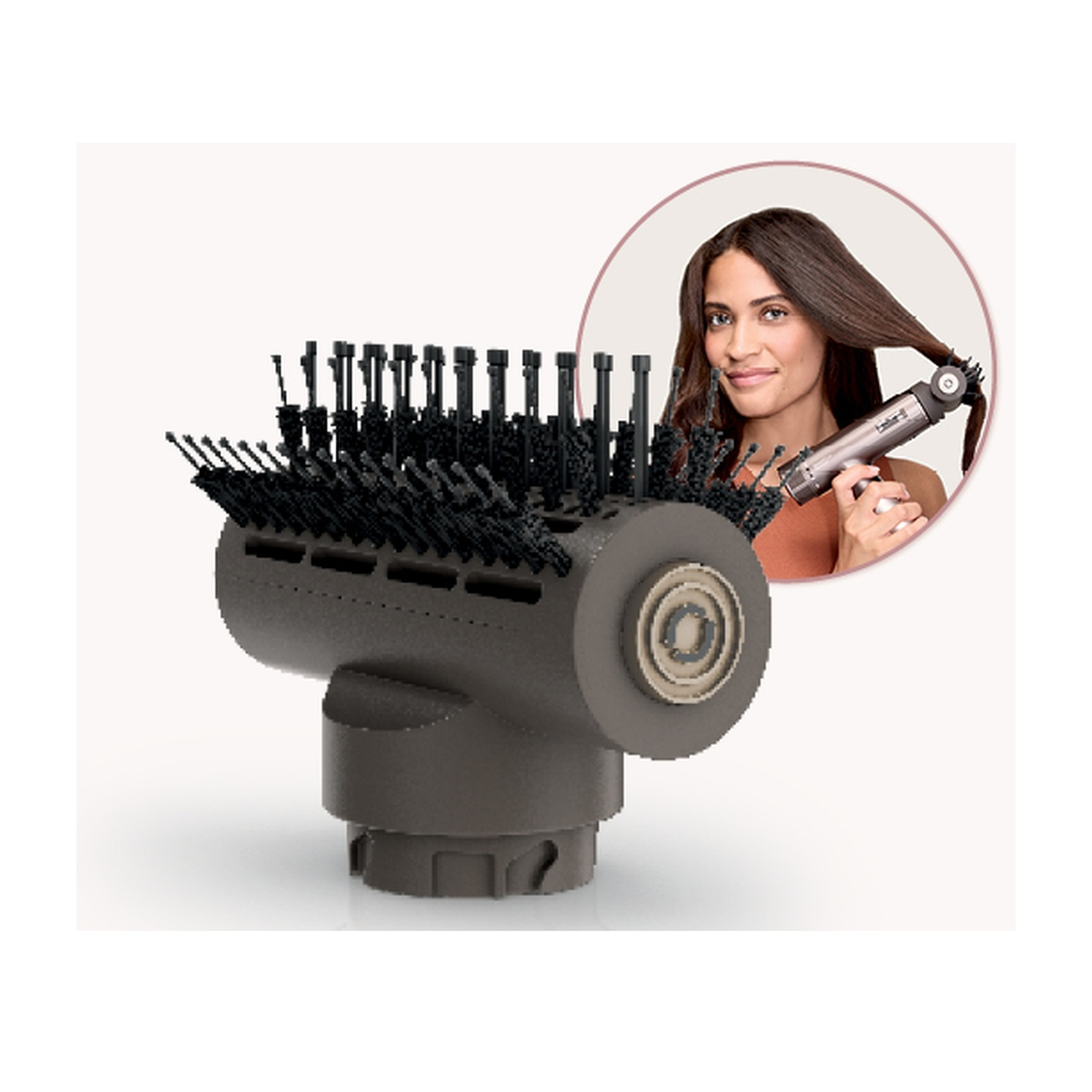 Strumento per lo styling dei capelli con testina a spazzola. Una donna lo usa sui suoi capelli. Lo strumento è grigio scuro. La donna sorride.