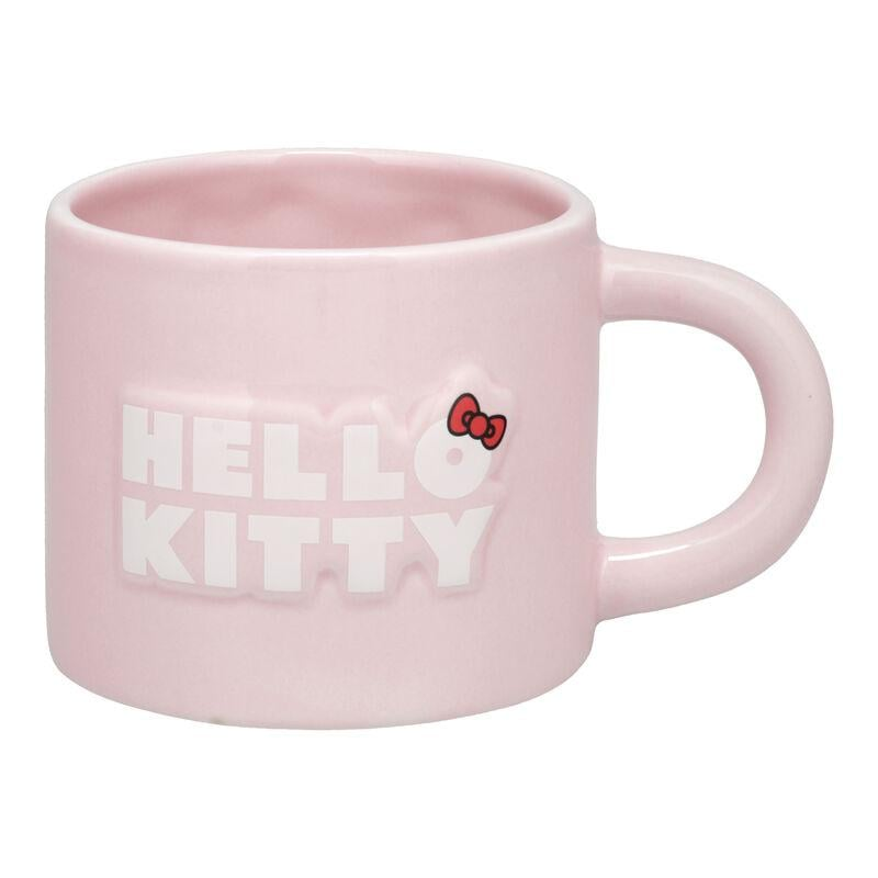Una taza rosa claro de Hello Kitty con asa. La taza tiene impreso 'HELLO KITTY' en el frente, con un lazo rojo.
