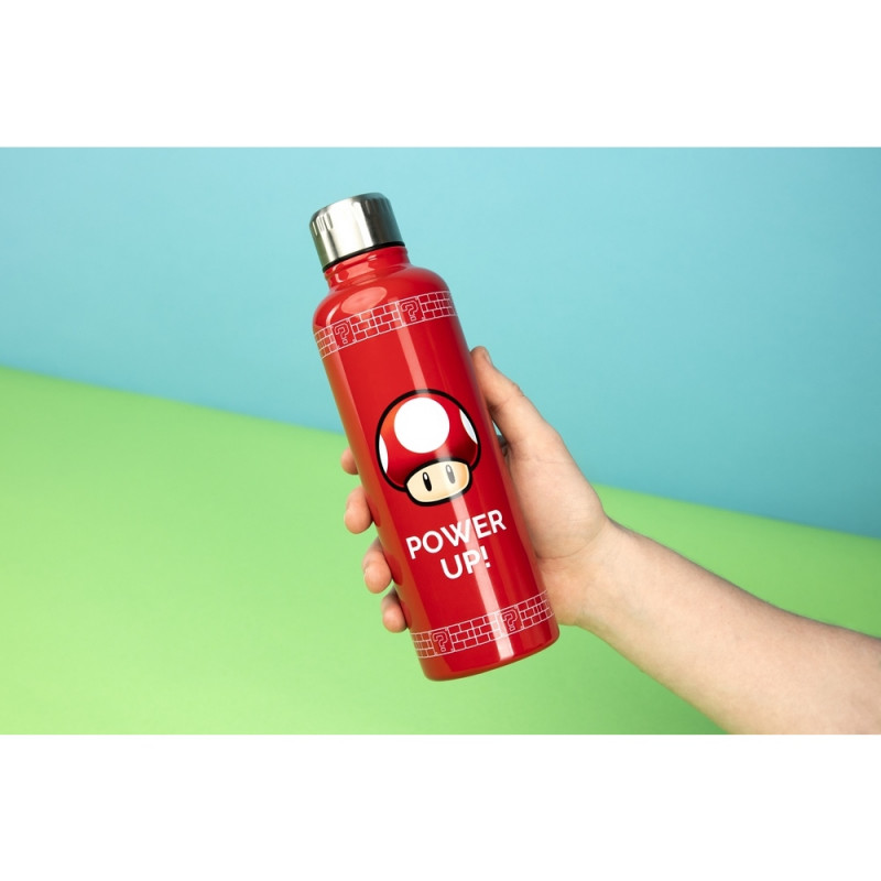 Una mano sostiene una botella de agua roja con un diseño de hongo de Super Mario y el texto 'POWER UP!'. El fondo es azul y verde.