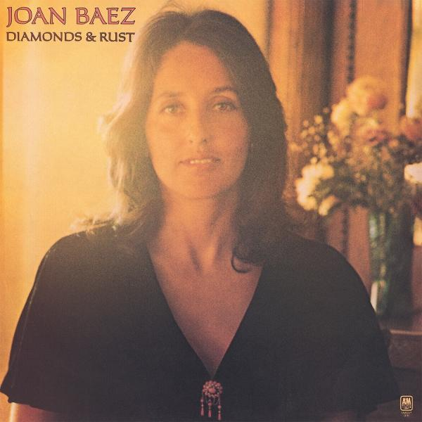 Joan Baez Albumcover. Sie trägt ein dunkles Oberteil mit Brosche. Text: "Joan Baez Diamonds & Rust". Blumen im Hintergrund.