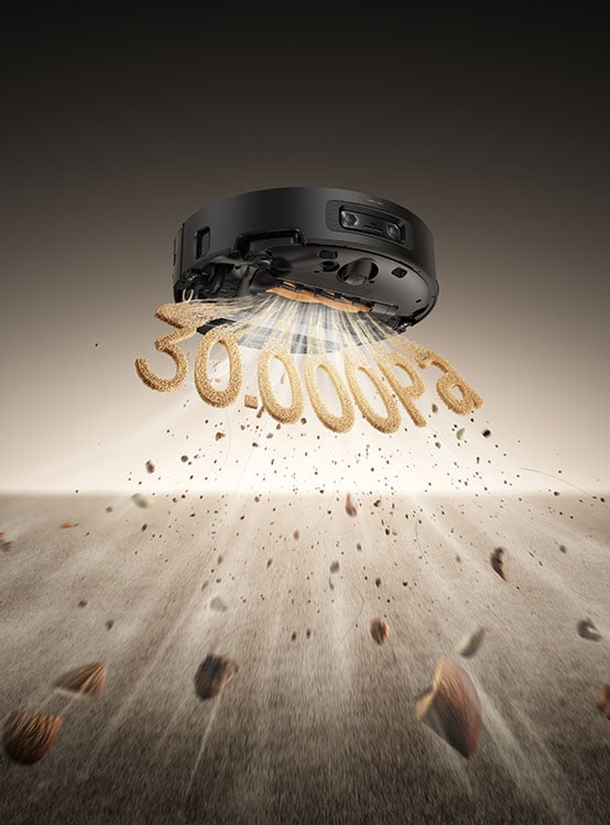 Czarny robot odkurzający z napisem 30 000Pa z piasku unosi się nad ziemią, sprzątając.