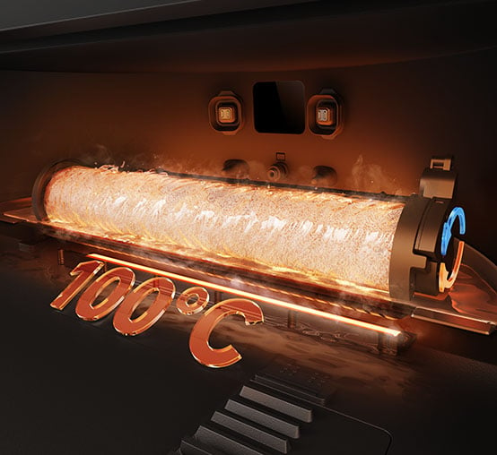 Wewnątrz maszyny świeci się podgrzany cylinder. Widoczny jest tekst '100°C'. Para unosi się. Po prawej stronie znajduje się niebieski i pomarańczowy element.
