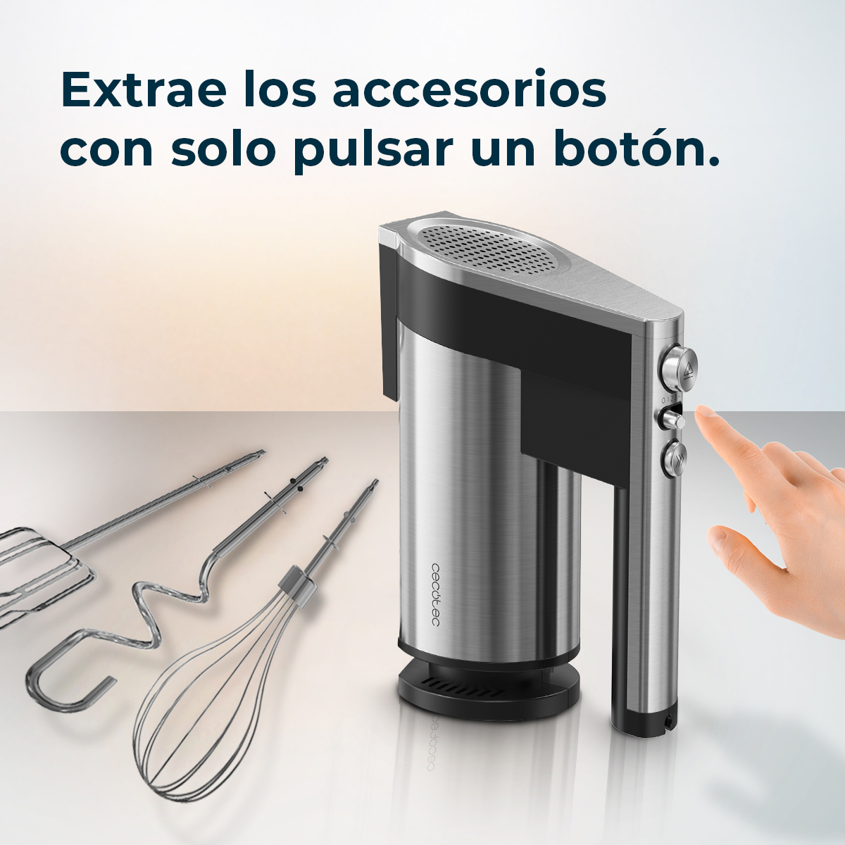 Una mano presiona un botón en una batidora de mano plateada. Tres accesorios están al lado. El texto dice: 'Retire los accesorios con un botón'.