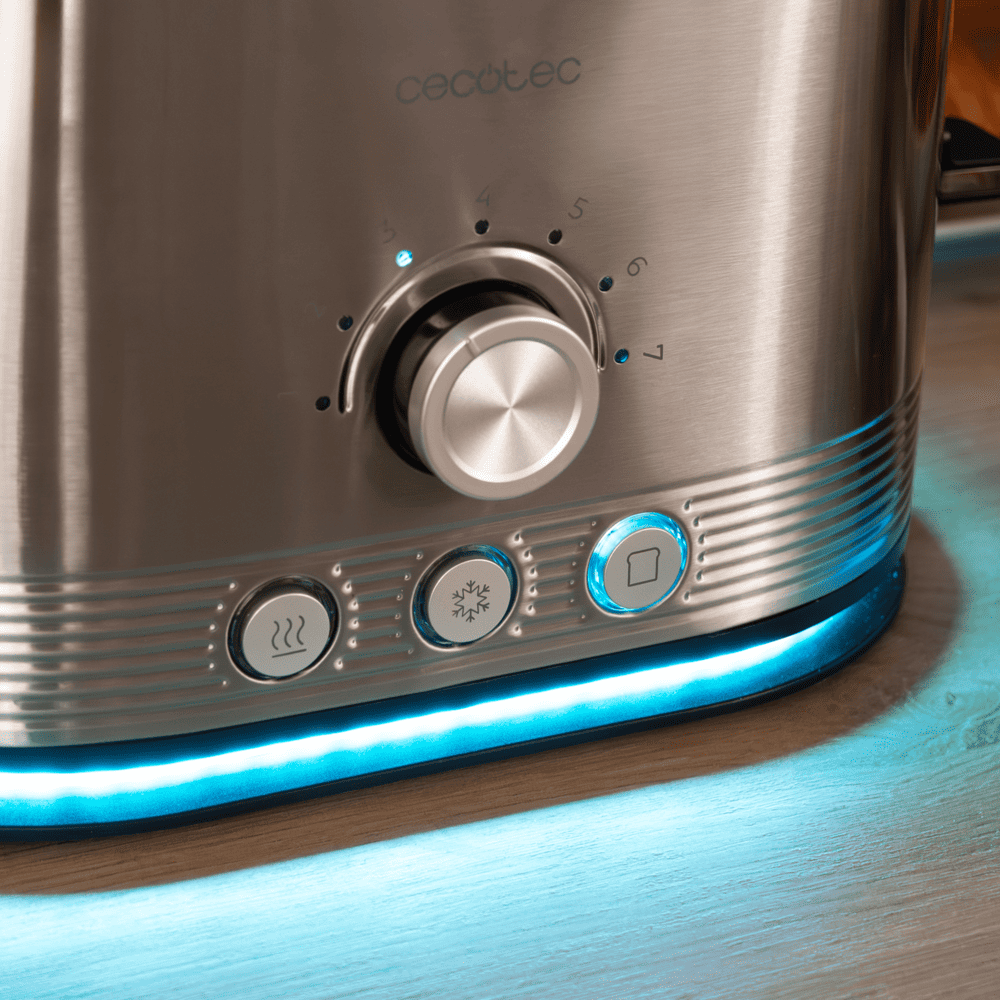 Primer plano de una tostadora de acero inoxidable con luces LED azules. Tiene un dial y botones para diferentes funciones, sobre una superficie de madera.