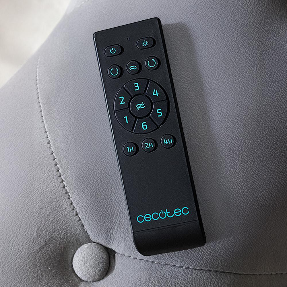 Un mando a distancia negro con botones y números, apoyado sobre una superficie gris acolchada. El mando tiene el logo 'Cecotec'.