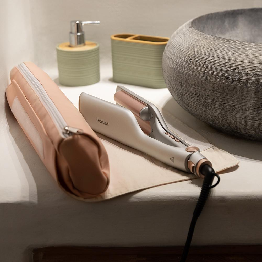 Una plancha y una funda rosa sobre una encimera con un dispensador de jabón y un lavabo al fondo.