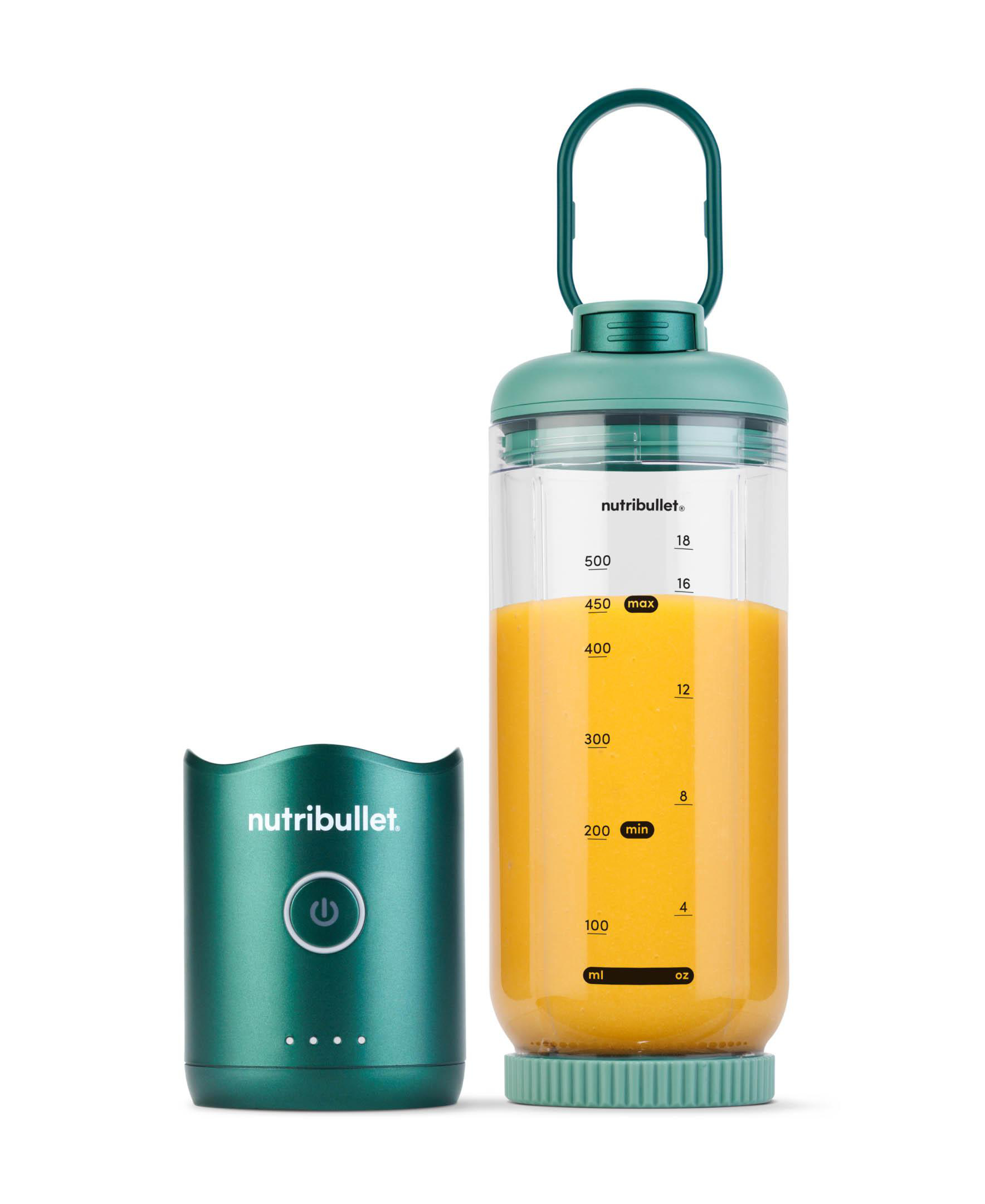 Ein grüner Nutribullet-Blender mit abgenommenem Sockel. Der Mixer enthält orangefarbene Flüssigkeit. Der Sockel links.