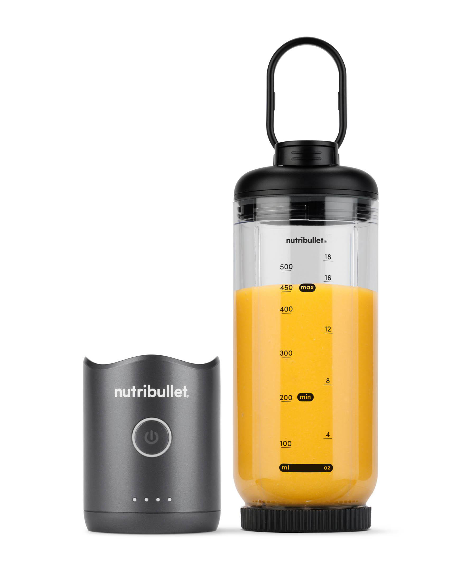 Ein Nutribullet-Mixer mit orangefarbener Flüssigkeit. Links befindet sich eine graue Basis. Der Mixer ist schwarz und klar.