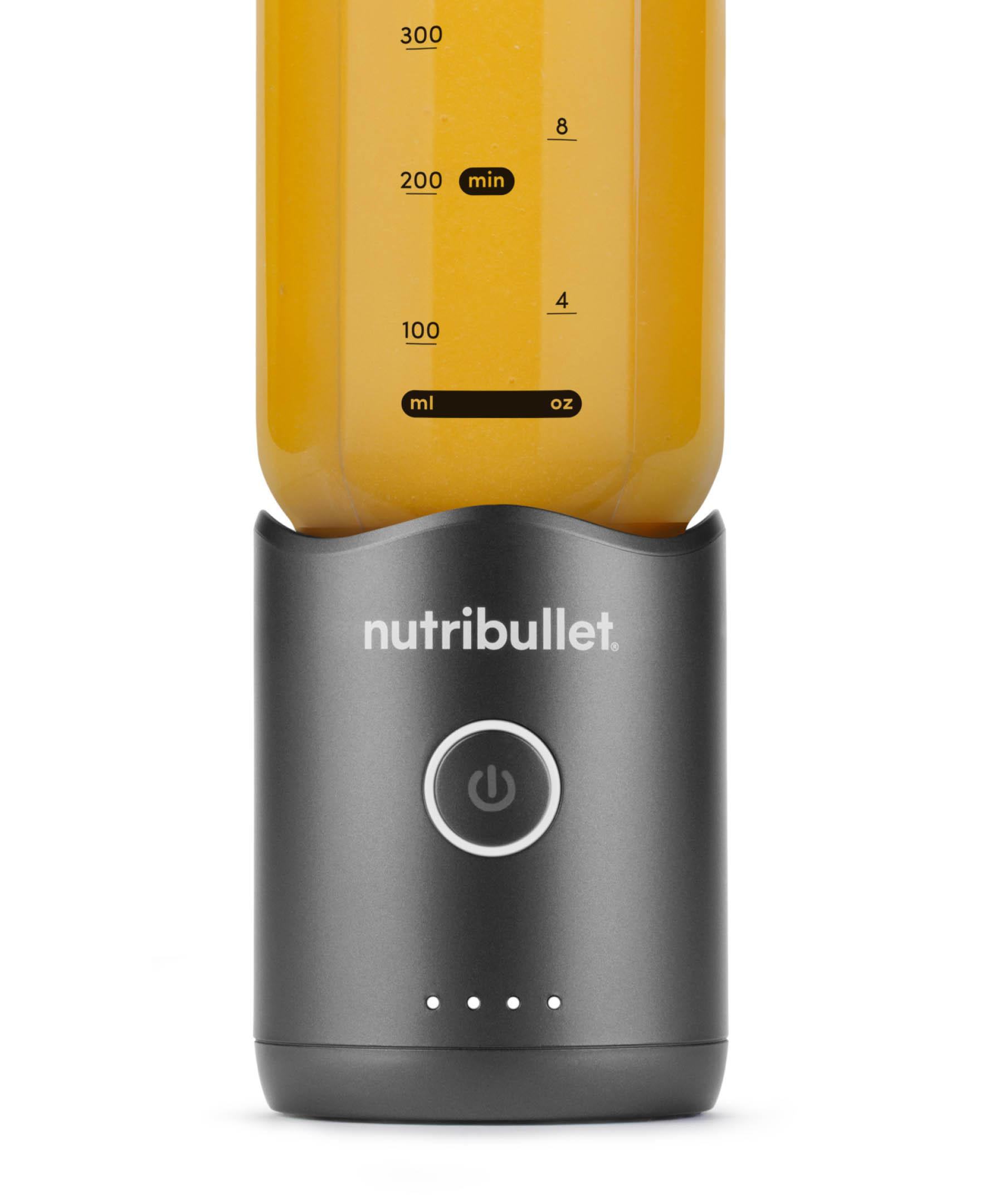 Ein Nutribullet-Mixer mit orangefarbener Flüssigkeit. Die Basis ist grau mit einem Ein-/Ausschalter und drei Kontrollleuchten.