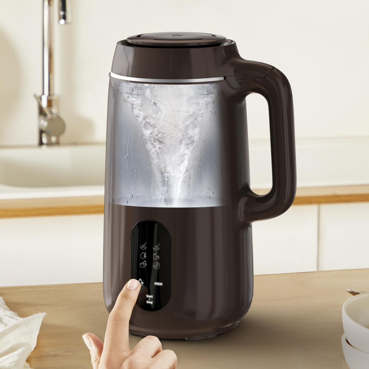 A brown appliance with a handle is making a vortex inside. A hand is pressing a button. Kitchen background.